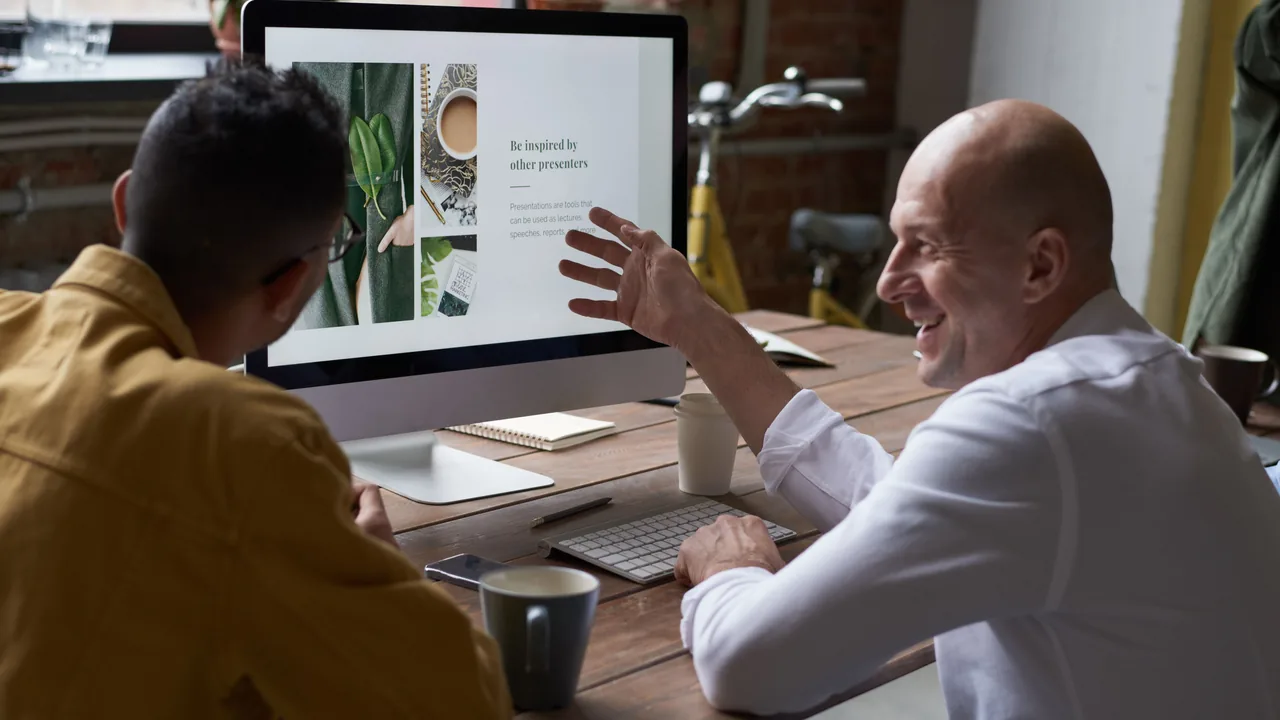 Two professionals discussing work at a desktop computer